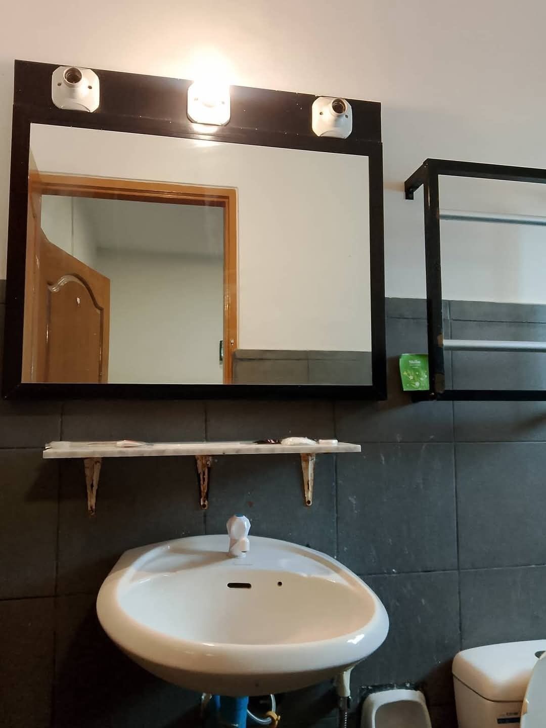 A bathroom with a white sink, a mirror, and a toilet.