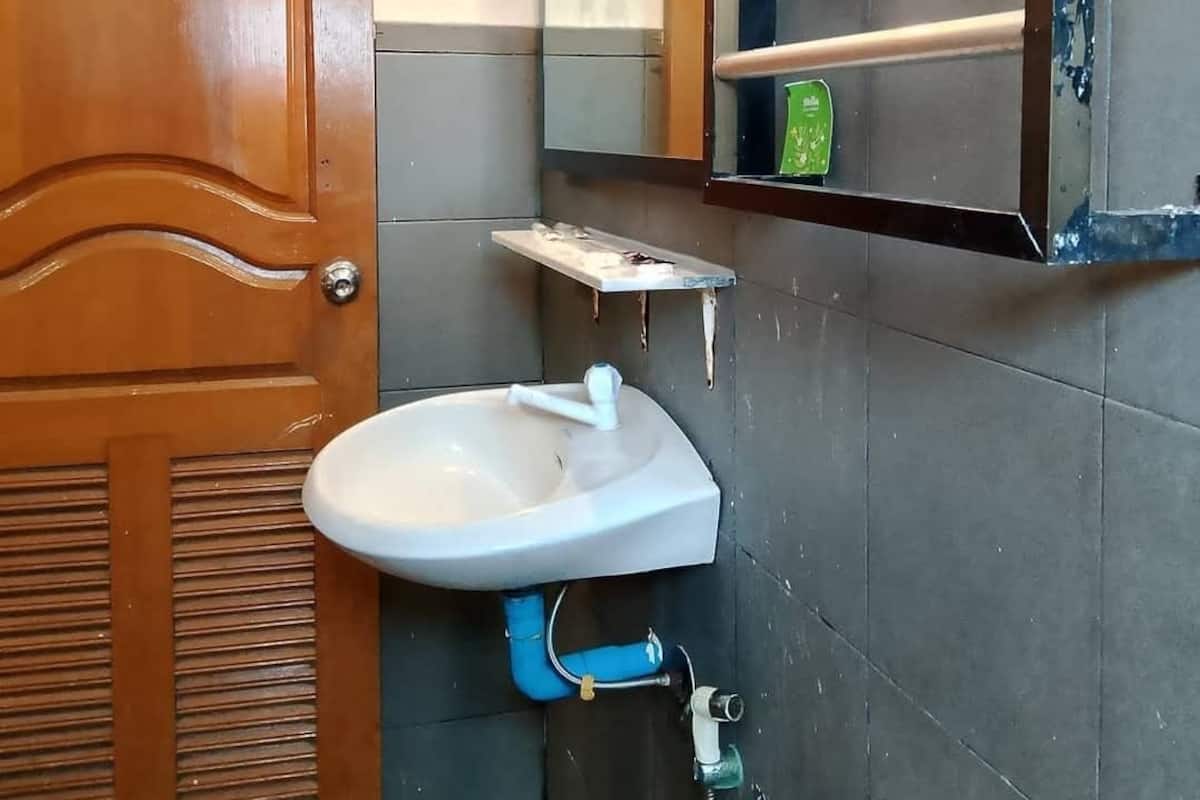 A bathroom with a wooden door, a white sink, a mirror, and a towel rack.