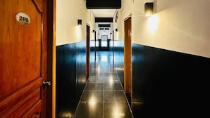 A hotel hallway with a wooden door labeled '202', black and white walls, and a tiled floor. - Triple H Hotel  (Yangon)