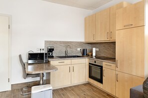 Una cocina compacta con microondas, cafetera, fregadero y horno.
