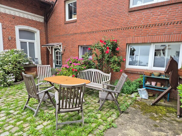 A brick house with a wooden table and chairs, a potted plant, and a window.