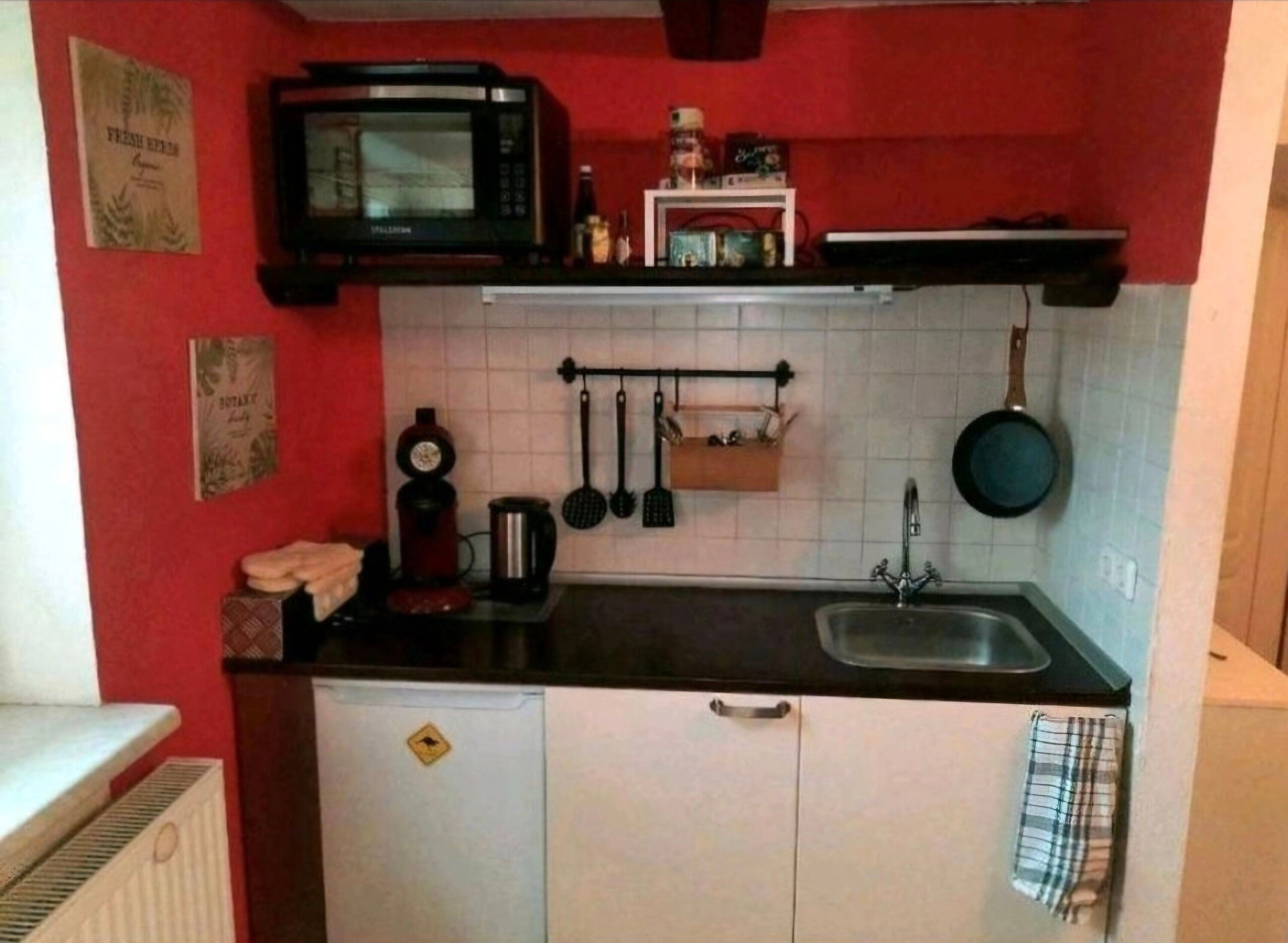 Une cuisine compacte équipée d’un four à micro-ondes, d’un évier et de divers ustensiles.