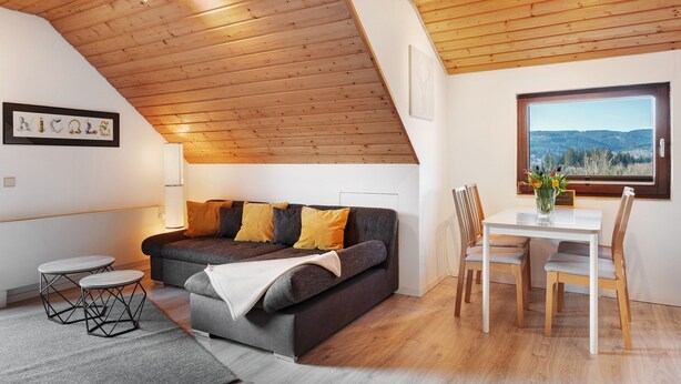 Un intérieur moderne avec un plafond en bois, un canapé, une table à manger et des chaises.