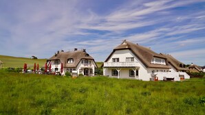 Två traditionella hus med halmtak på en gräsklädd åker.