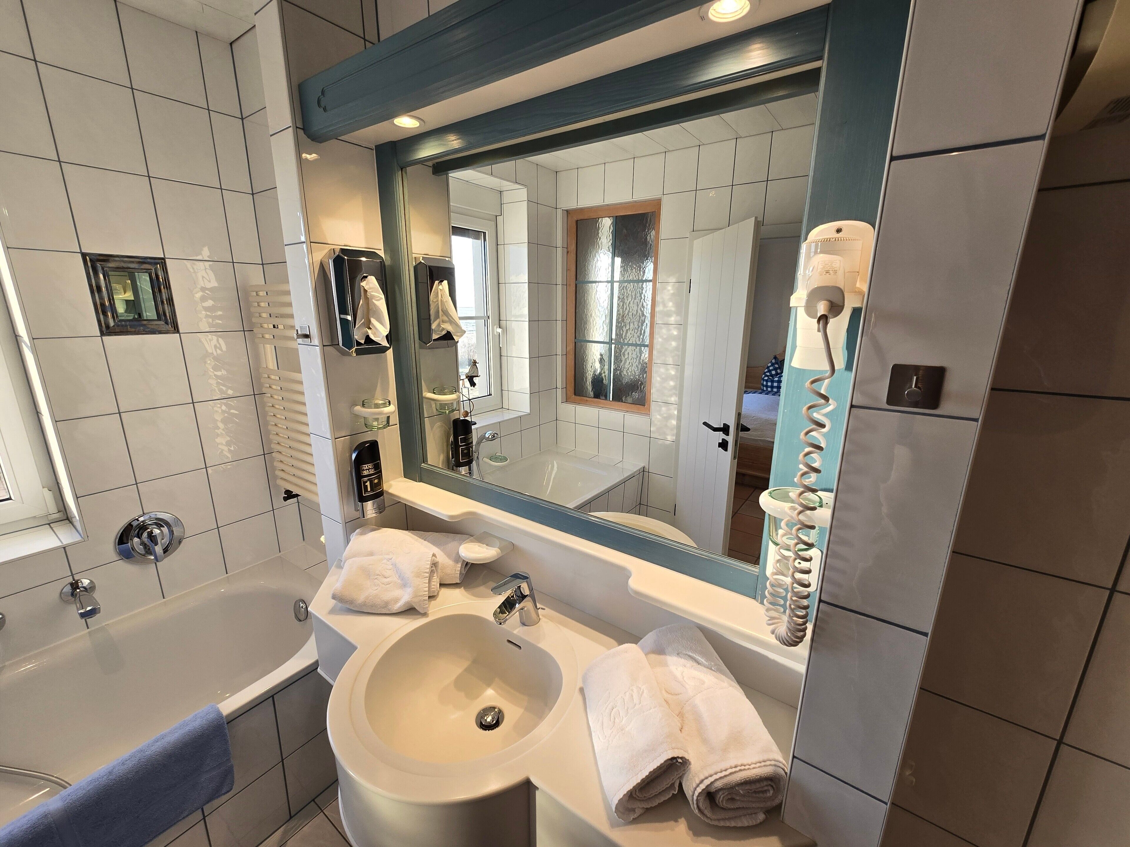 Une salle de bain moderne avec une baignoire, un grand lavabo, un miroir et un porte-serviettes.