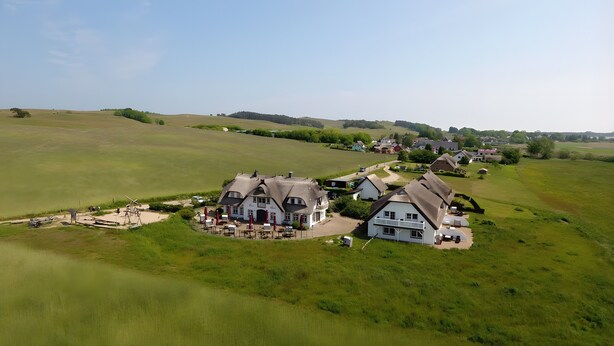 A rural village with traditional houses, a central building with outdoor seating, and a large open field. - Apartment 'Seeschwalbe' with Sea View, Shared Terrace and Wi-Fi (Mönchgut)