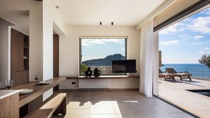 A modern kitchen with a large window, a built-in TV, and a dining area with a bench and table.
