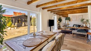 Amplia sala de estar con vigas de madera, un ventanal y vistas al exterior.