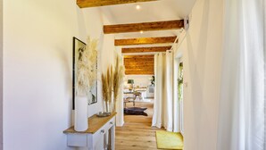 Un pasillo con vigas de madera, pared blanca, una consola de madera y un tapete amarillo.