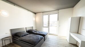 A modern bedroom with a bed, bedside table, and a desk. - Room 'Zimmer 2' with Wi-Fi (Dußlingen)