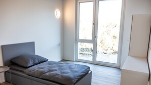 A modern bedroom with a bed, a bedside table, and a large window. - Room 'Zimmer 3' with Wi-Fi (Dußlingen)