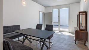 Een moderne kamer met een eettafel, banken en een houten kast.