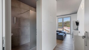 Een moderne hotelkamer met een douche, een balkon met uitzicht en een minimalistisch design.