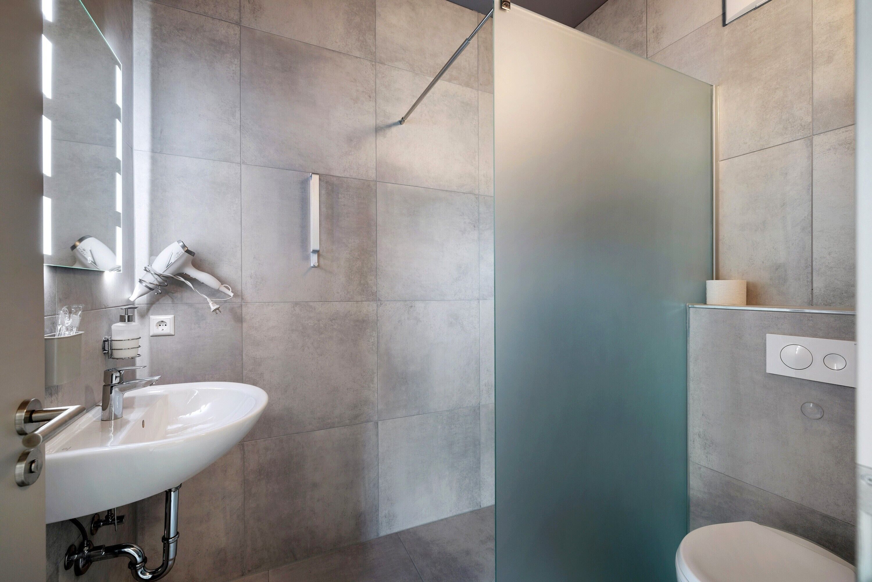 A modern bathroom with a sink, mirror, and shower.