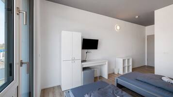 A modern bedroom with a bed, desk, and TV.