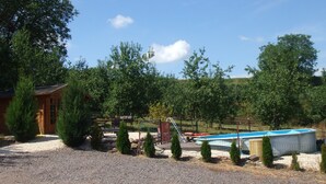 Una zona de grava amb una piscina, una cabana de fusta i un jardí tancat per una tanca.