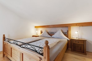 Un lit en bois avec une tête de lit en métal, deux tables de chevet avec des lampes et une petite armoire en bois.