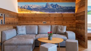 A modern living room with a wooden wall panel and a large mountain view mural.