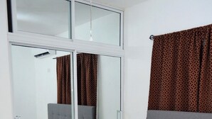 A bedroom with a bed, a wardrobe, and a mirror.