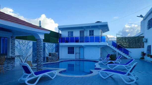 A modern pool area with lounge chairs, a staircase, and a two-story building with a balcony.
