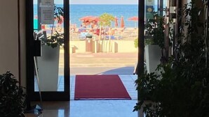 A hotel entrance with a view of a beach and ocean. - Hotel Spiaggia D'Oro (Mondolfo)