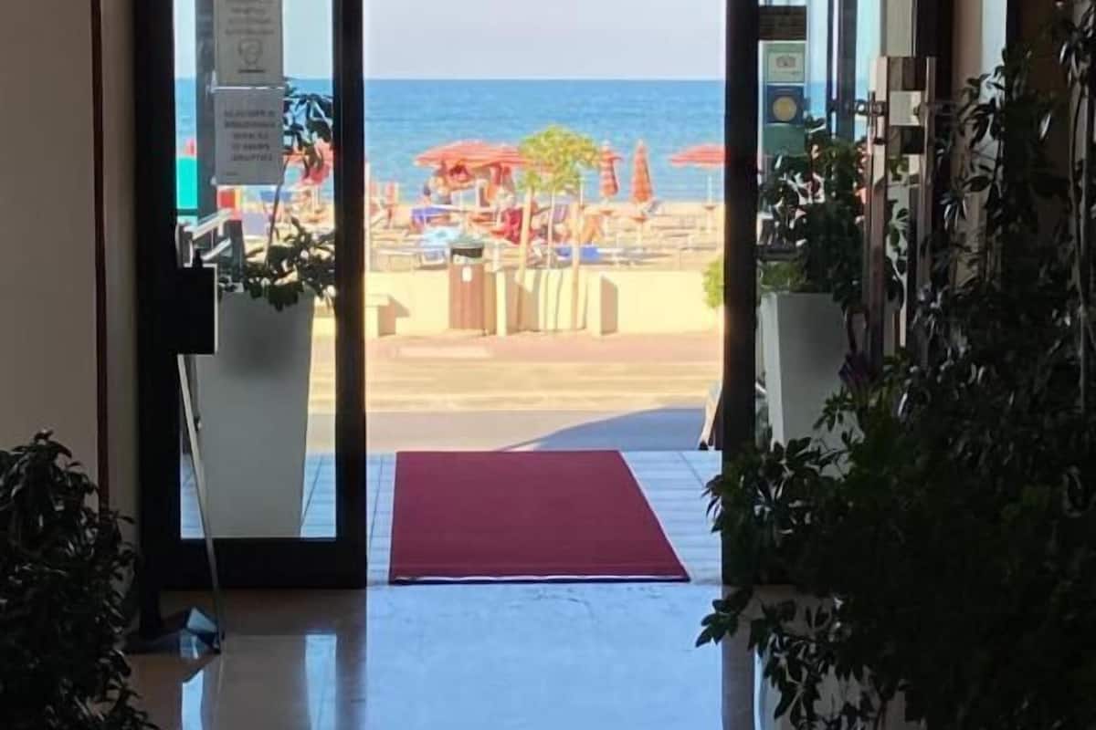A hotel entrance with a view of a beach and ocean.