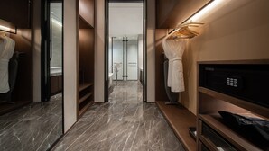 Ett modernt hotellbadrum med ett marmorgolv, en torkställning för badrockar och en mikrovågsugn.