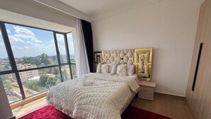 A bedroom with a large window, a bed with a red rug, and a modern headboard. - The loftel luxury  2-bedroom apartment with WiFi, AC in wonderful Nairobi (Nairobi)