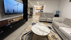 A modern living room with a flat-screen TV, a sofa, a coffee table, and a dining area in the background. - The loftel luxury  2-bedroom apartment with WiFi, AC in wonderful Nairobi (Nairobi)