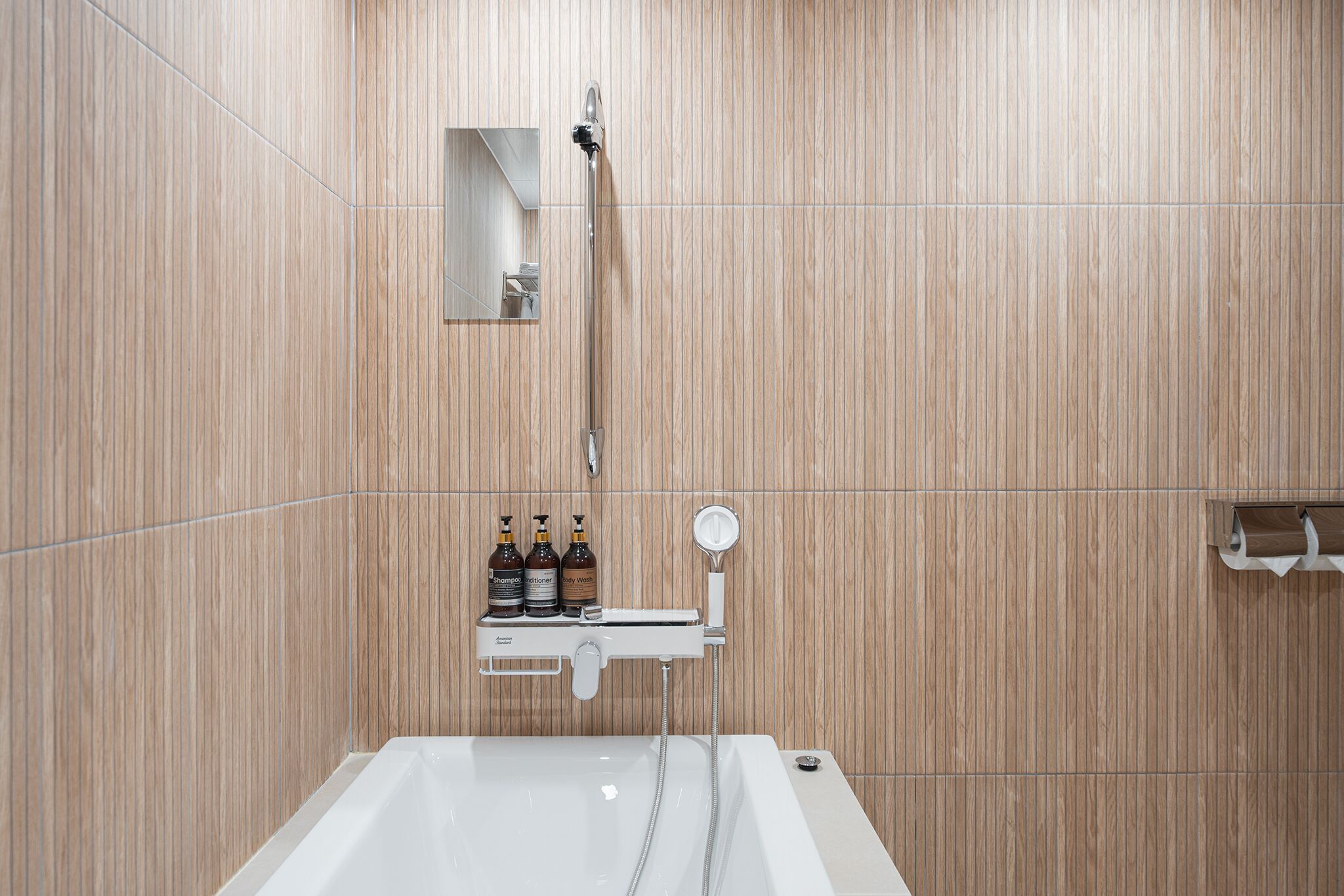 A modern bathroom with a bathtub, a shower, and a shelf with toiletries.