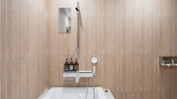 A modern bathroom with a bathtub, a shower, and a shelf with toiletries.
