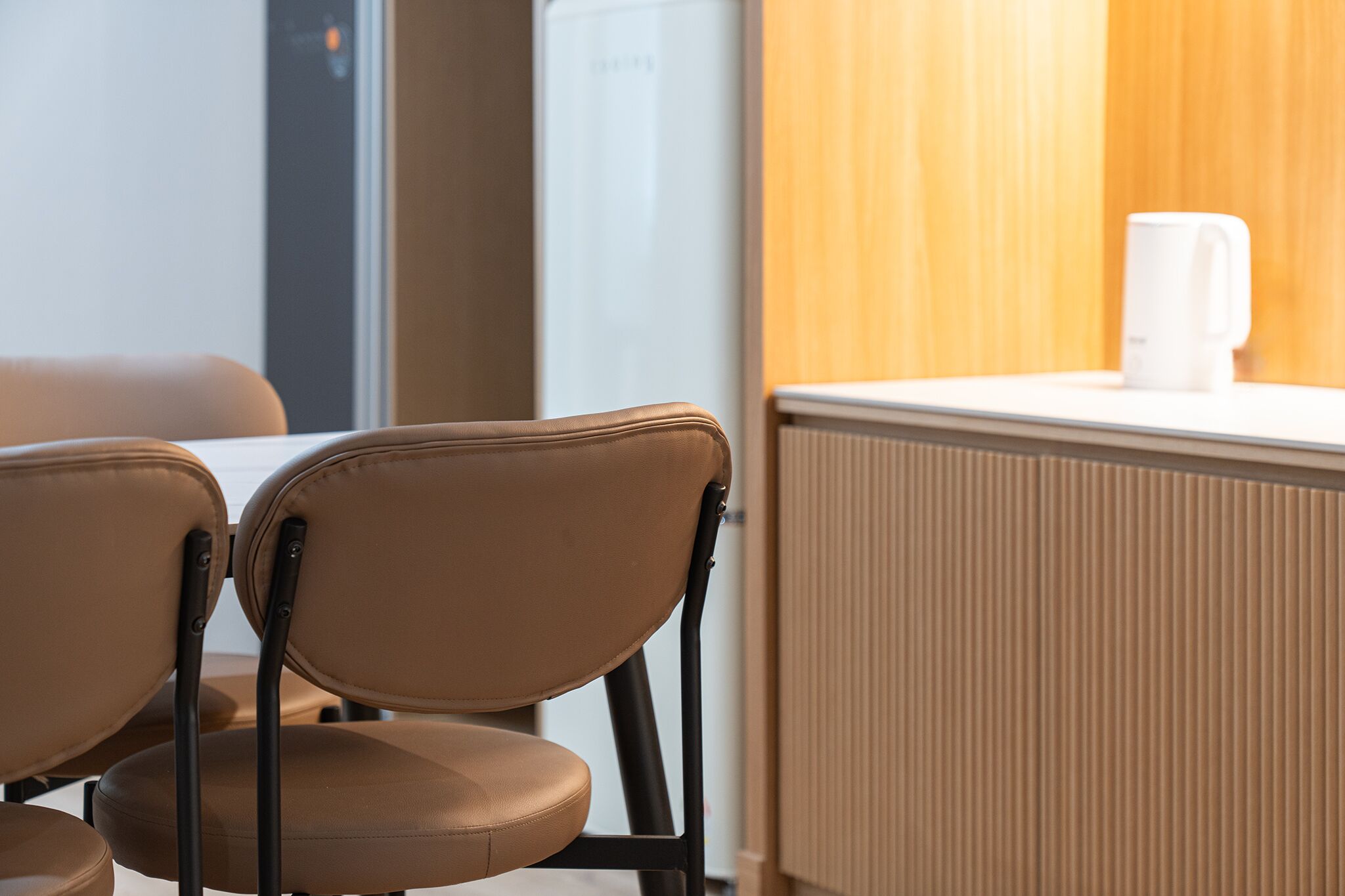 Een zithoek met twee stoelen en een tafel, een witte koffiezetapparaat en een radiator.