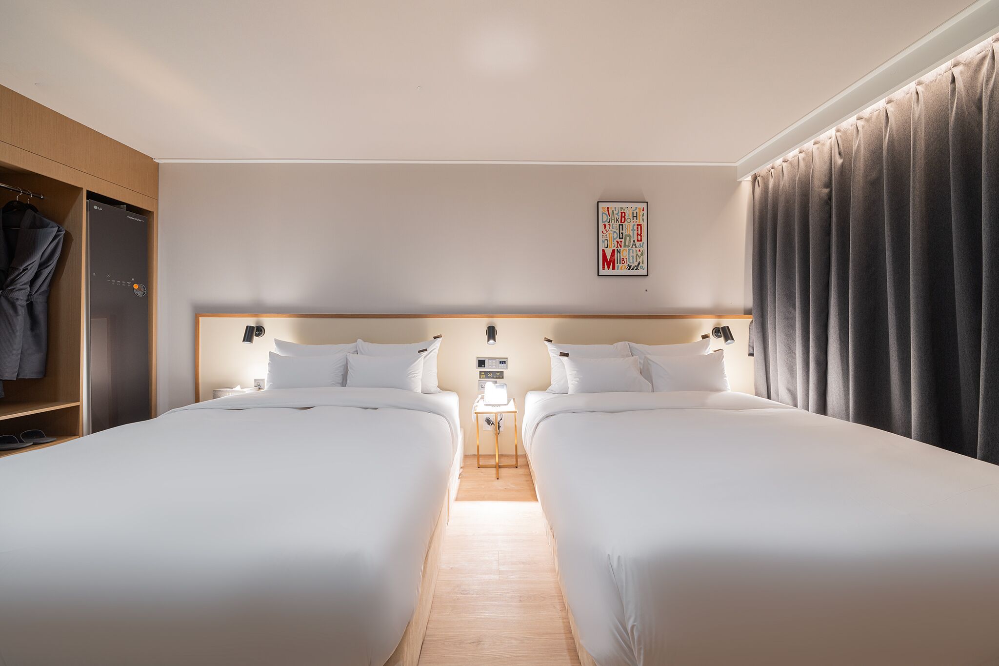 Una habitación de hotel con dos camas individuales, un armario, una mesita de noche y una obra de arte colgada en la pared.