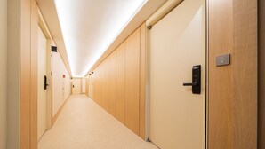 A long, narrow hallway with wooden doors and a carpeted floor. - Cheonan H-Avenue Cheonan Buldang (Cheonan)