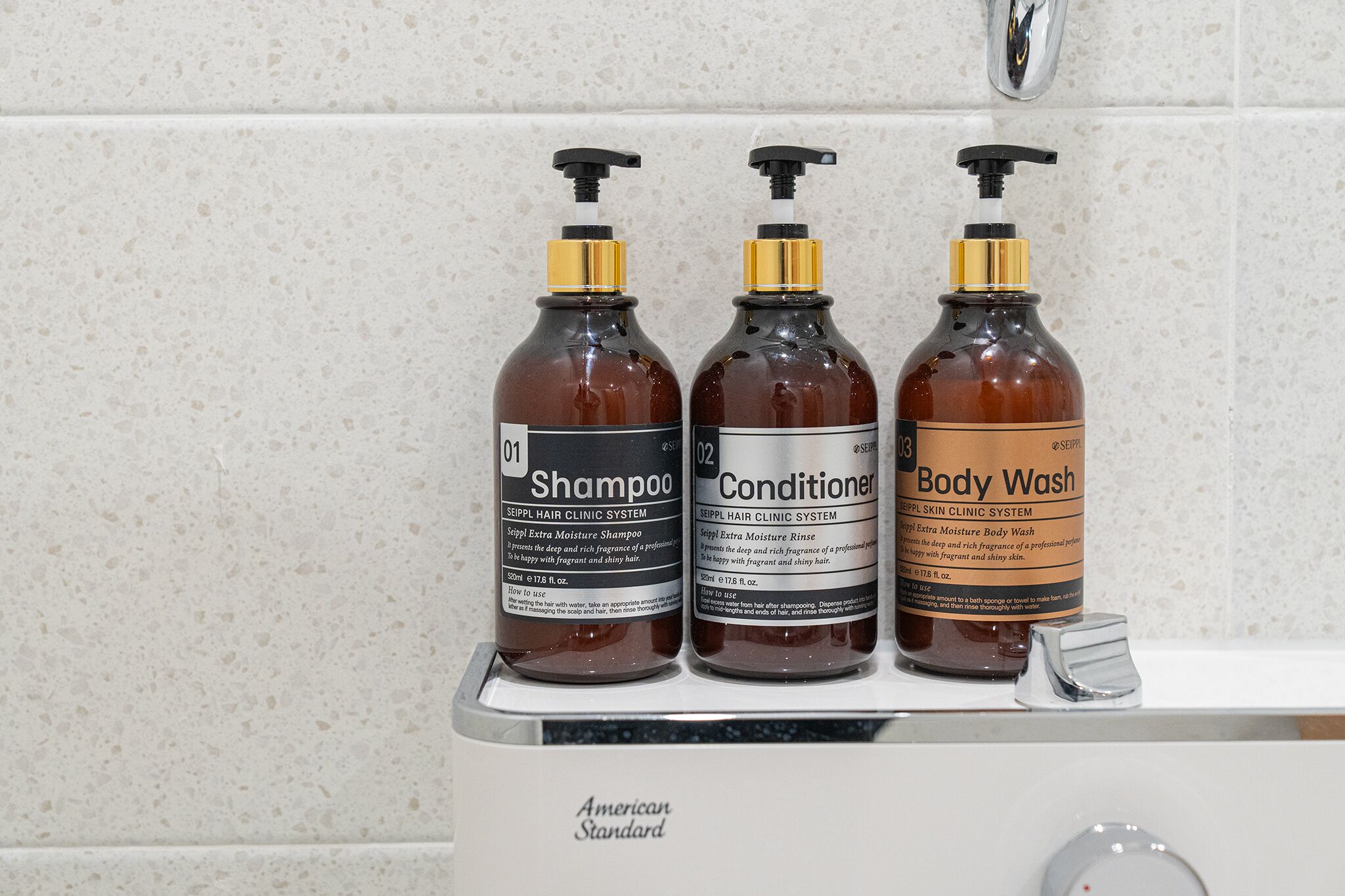 Tres botellas de productos para el cabello sobre una encimera de baño.