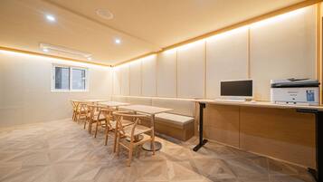Una sala de reuniones moderna con una mesa larga, sillas, un banco, una computadora e impresora.