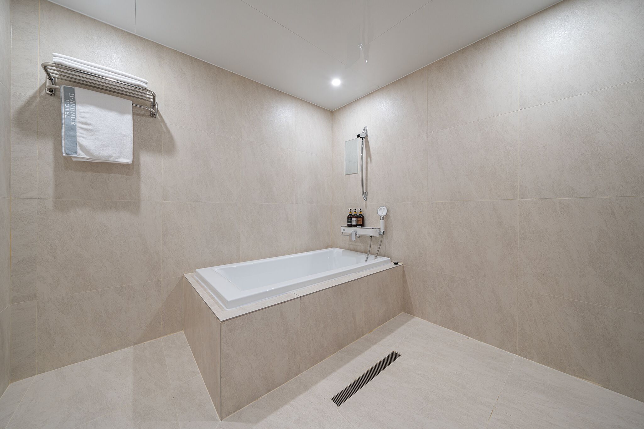 A modern bathroom with a bathtub, a towel rack, and a showerhead.