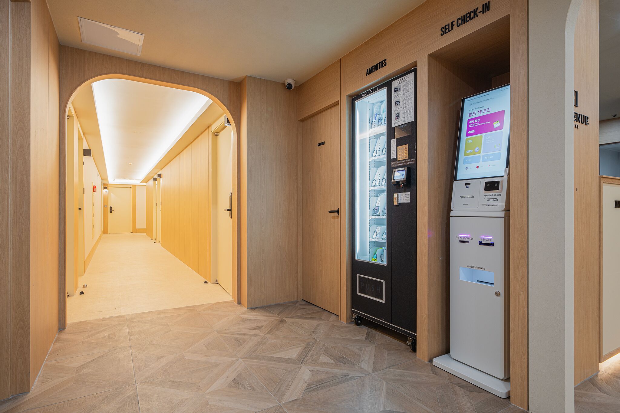 A hotel corridor with a self-check-in kiosk and a reception area.