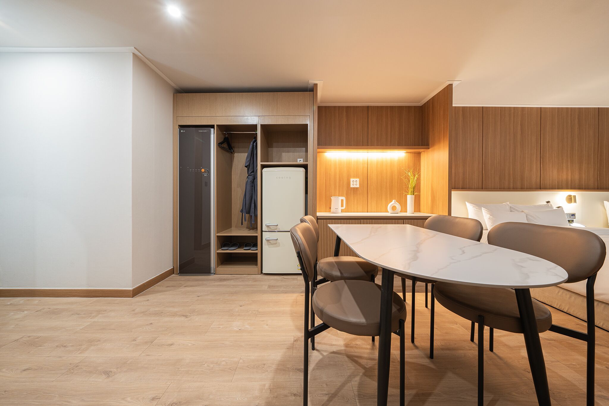 A modern kitchen with a dining area, wooden cabinets, and a built-in refrigerator.