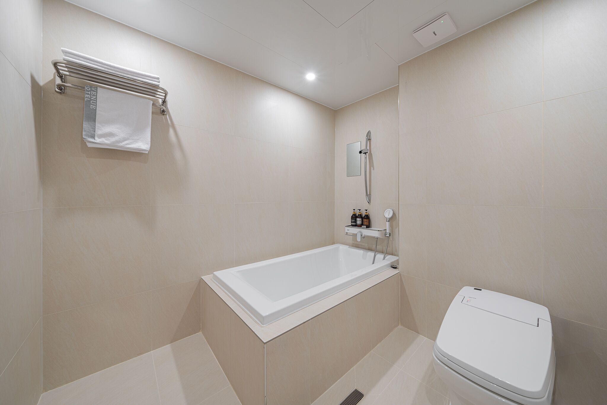 A modern bathroom with a bathtub, toilet, and a towel rack.