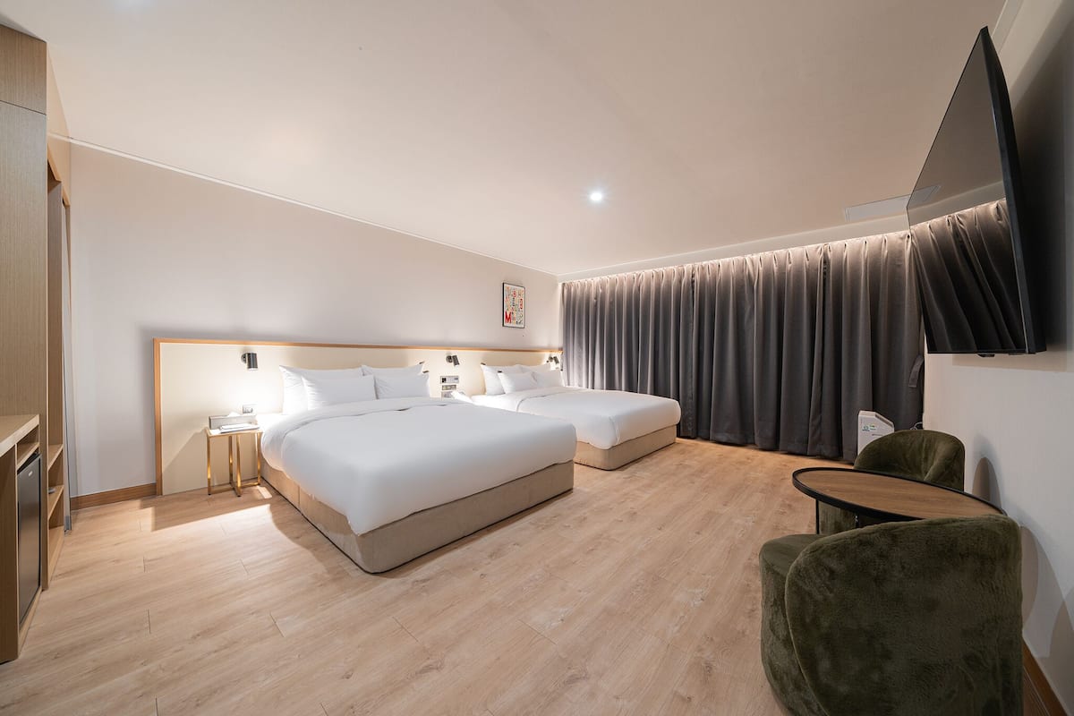 A hotel room with two beds, a flat-screen TV, a desk, and a chair.