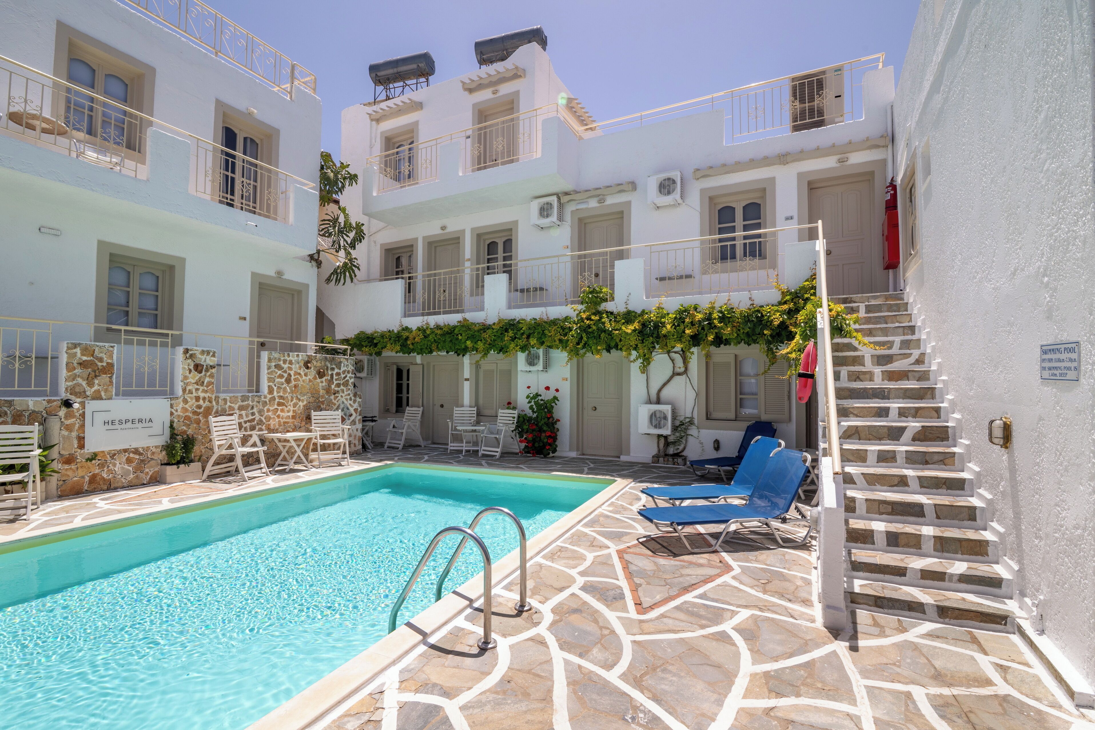A pool area with lounge chairs, a staircase, and a sign indicating a swimming pool.