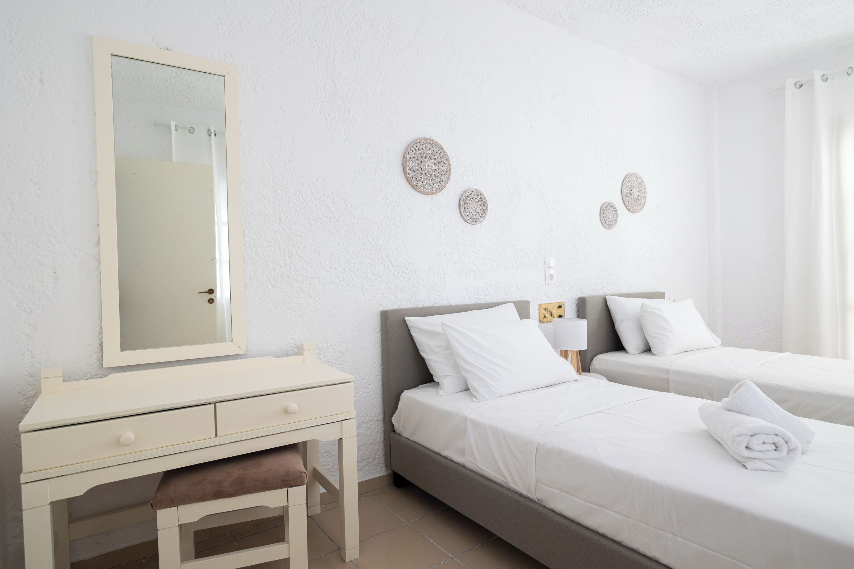 Een hotelkamer met twee bedden, een nachtkastje, een spiegel en decoratie aan de muur.