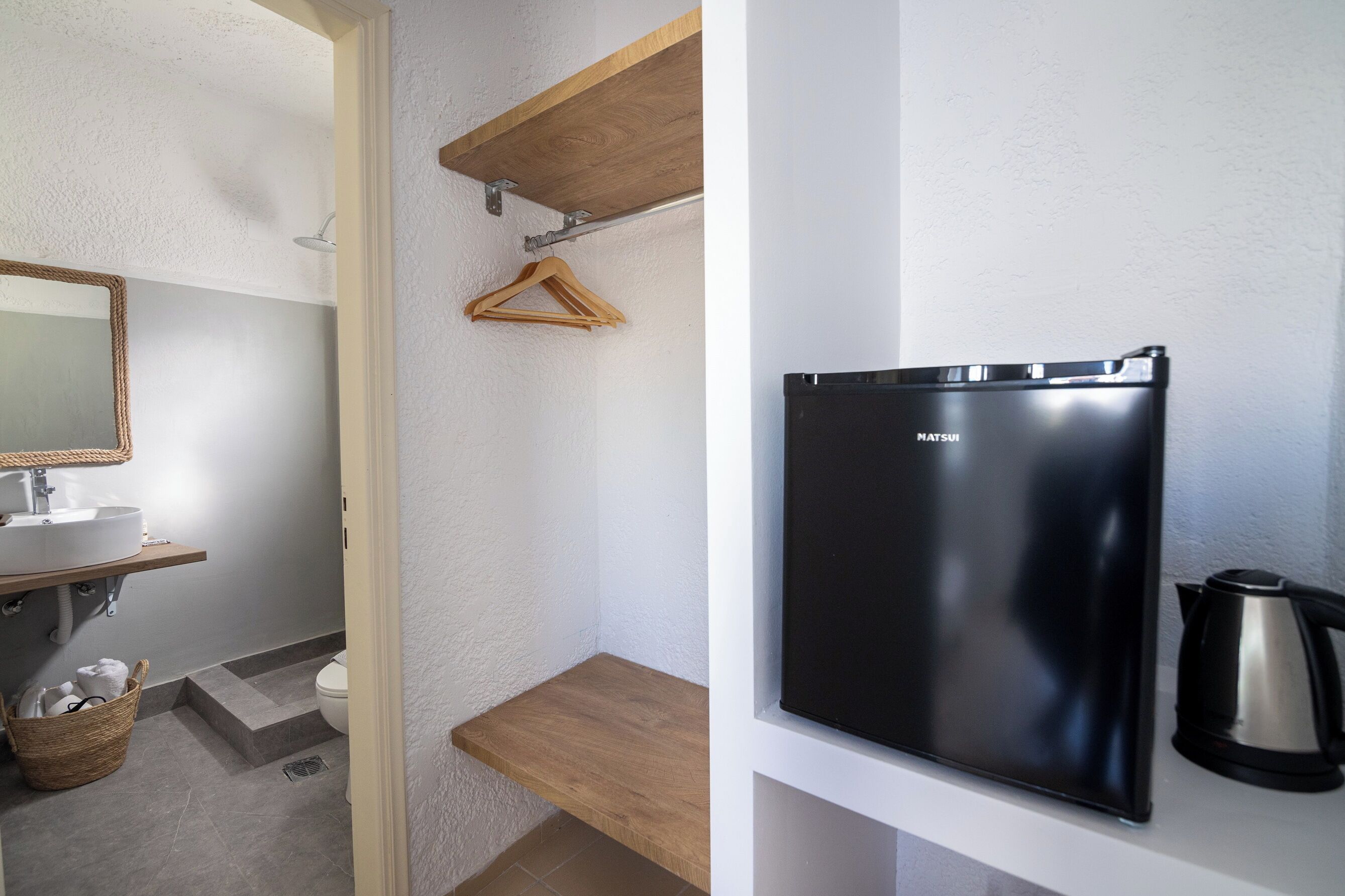 Ein kleines Badezimmer mit einem weißen Waschbecken, einer Holzablage und einem schwarzen Kühlschrank.