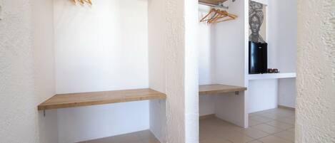 A room with a white textured wall, a wooden shelf, and a black refrigerator.