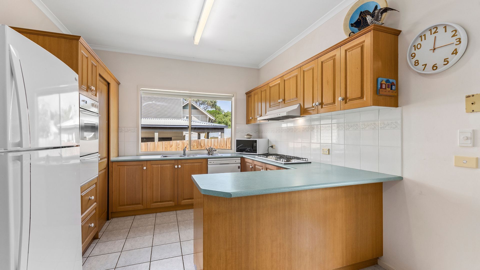 A kitchen with wooden cabinets, a white refrigerator, a microwave, and a gas stove.