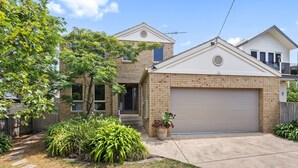 A two-story house with a brick facade, a garage, and a well-maintained garden with various plants. - The Lighthouse Point Lonsdale (Point Lonsdale)