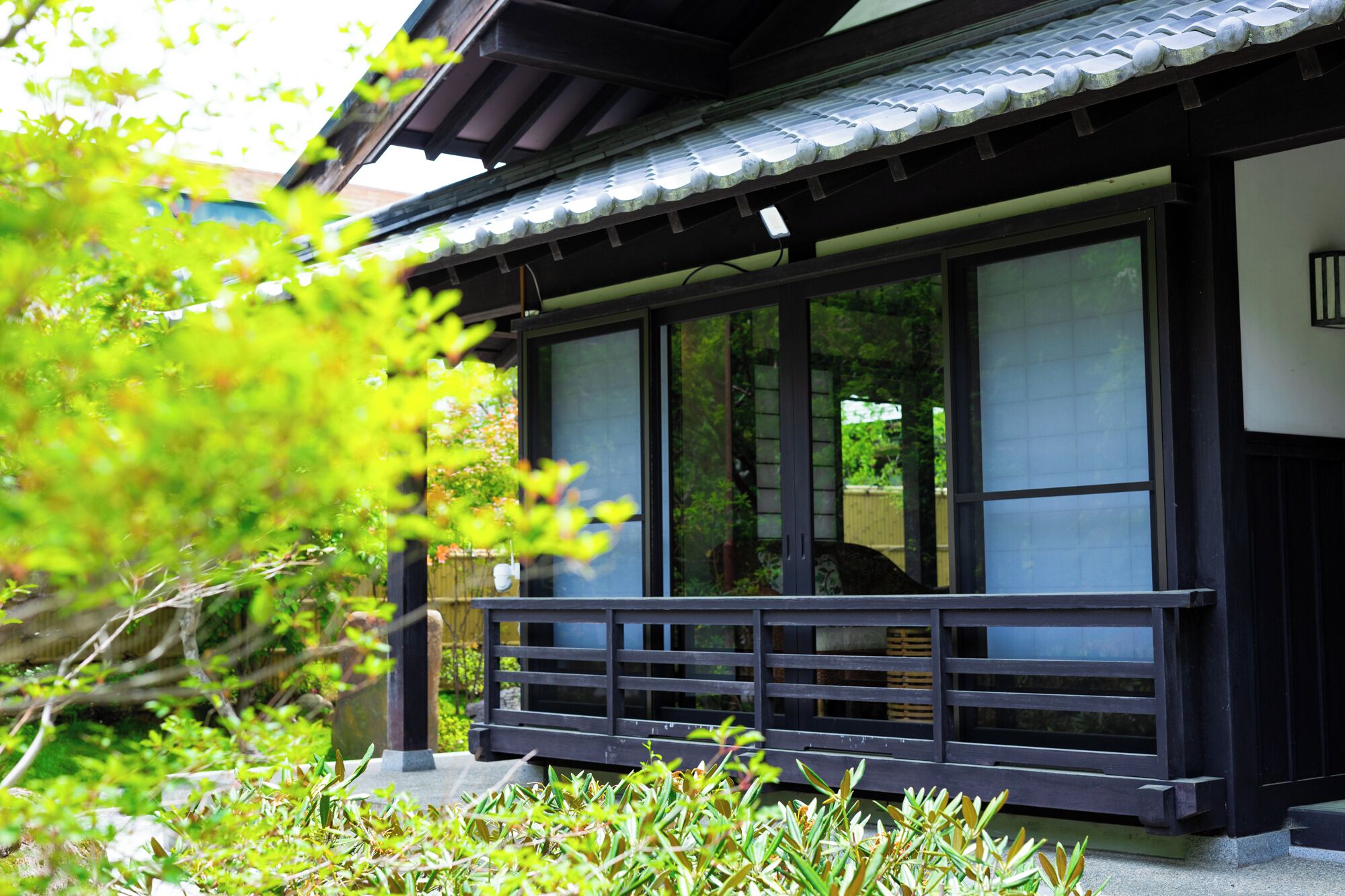 Un edificio japonés tradicional con amplias puertas correderas, un porche de madera y un techo de tejas.