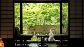 A room with tatami flooring, a low table, two chairs, and a view of a lush garden through a sliding door. - Shinshu Omachi Onsen Ryoan Kawaki (Omachi)