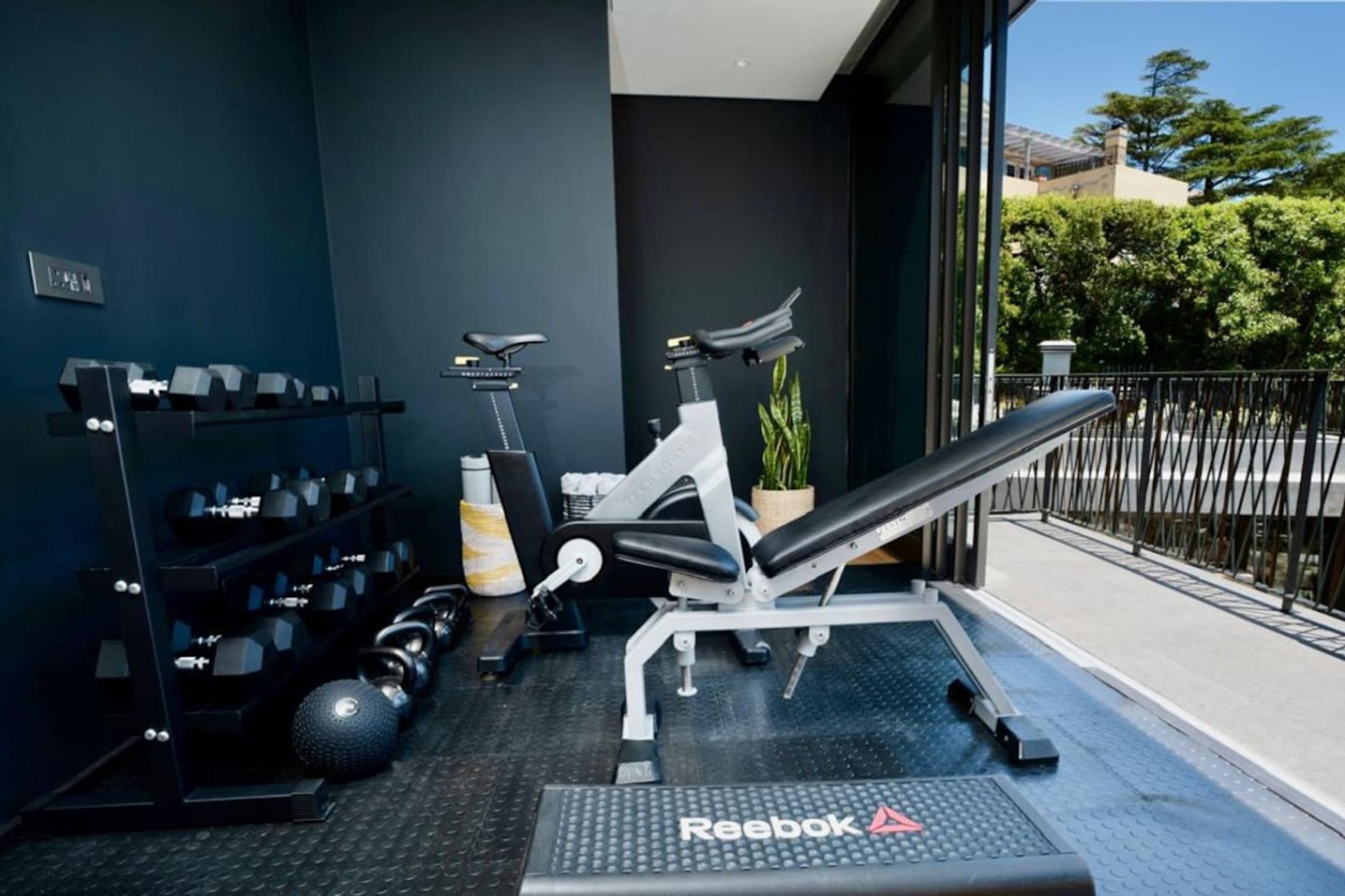 Uma academia com equipamentos de exercícios, um banco e halteres.